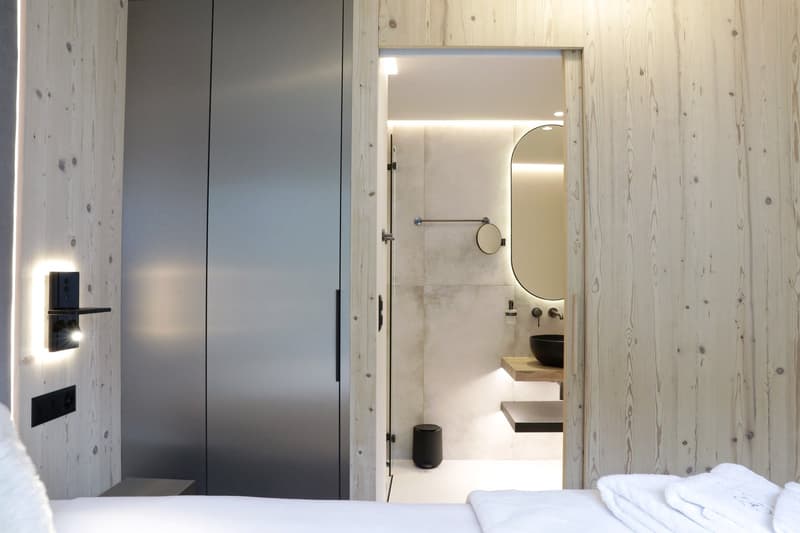Modern minimalist bathroom with wooden walls, sink, mirror, toilet, and a light fixture