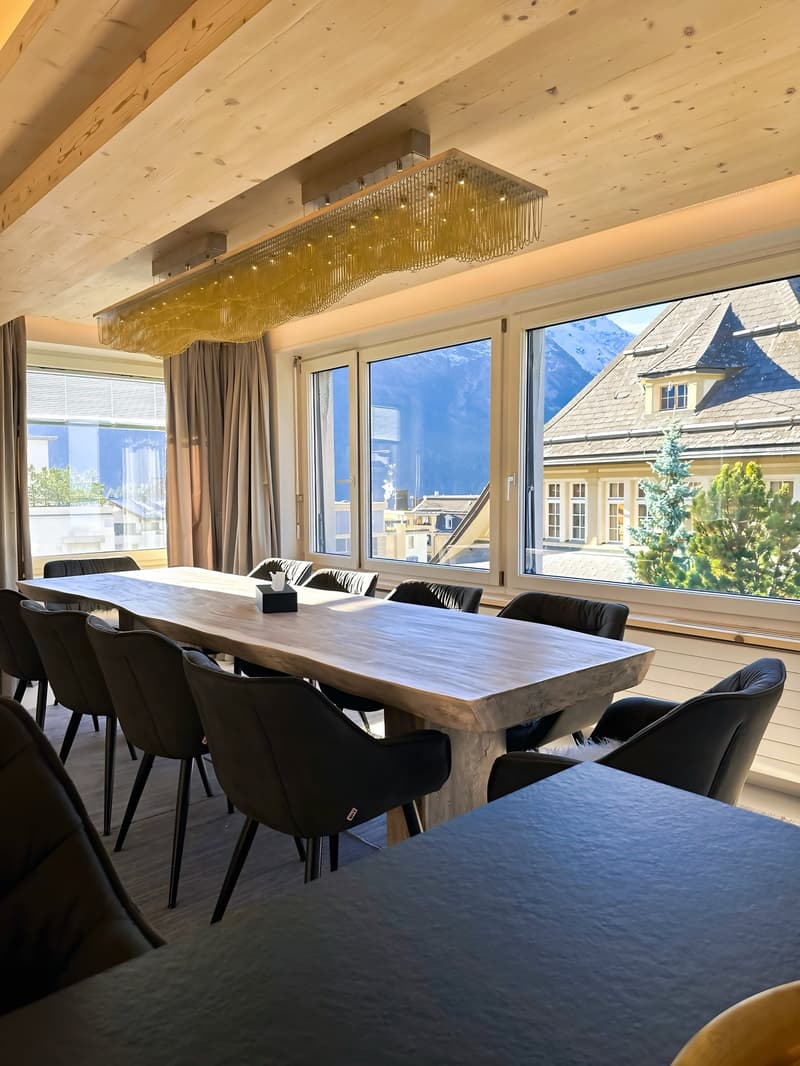 large meeting room, long wooden table, black leather chairs, large windows, wooden ceilings