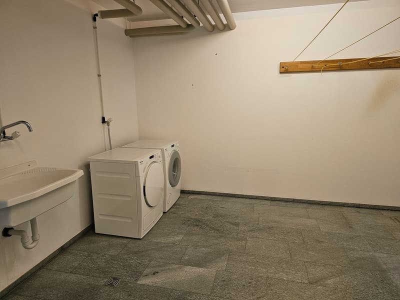 A small laundry room with a sink, washing machine, and dryer.