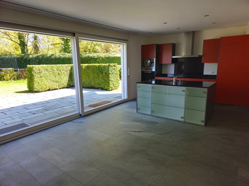 Modern kitchen with large sliding doors, kitchen island, and a view of the garden.