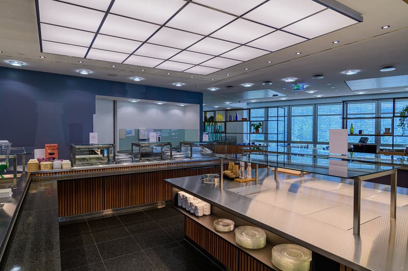 modern kitchen area with stainless steel counters, glass display cases, wooden cabinets, and tiled flooring