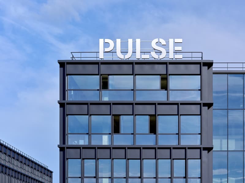 High-rise office building, modern architecture, many glass windows, rooftop balcony, 'PULSE' signage