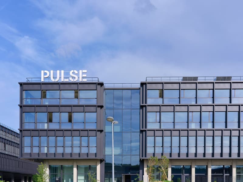 office building, modern design, glass windows, solar panels on roof, entrance on ground floor