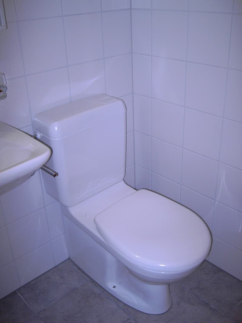 modern bathroom with white toilet, white sink, white tiles on walls and floor