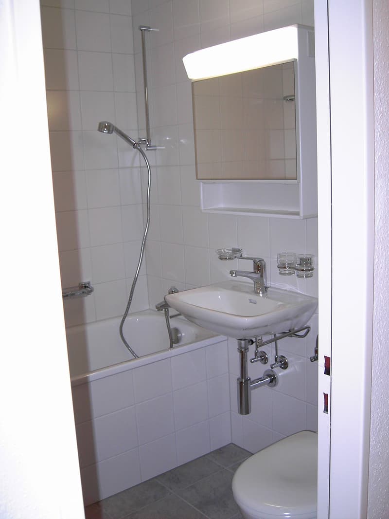 white tiled bathroom with bathtub, sink, and toilet