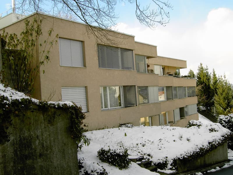 Multi-story building, beige exterior, several windows, balconies, snowy surroundings