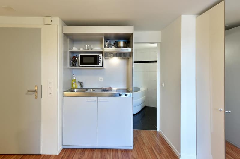 compact kitchen with sink, countertop, microwave, refrigerator, cabinet, and faucet
