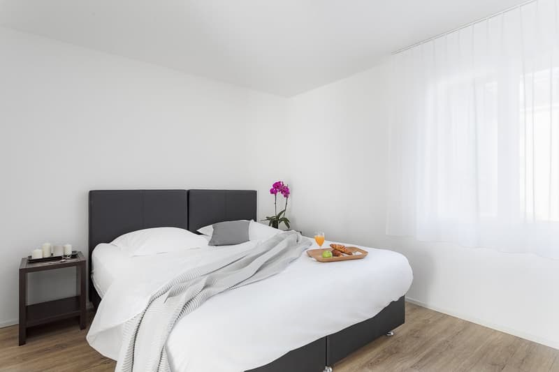 Bedroom: bed, pillows, tray with food, candles, white walls, white curtains