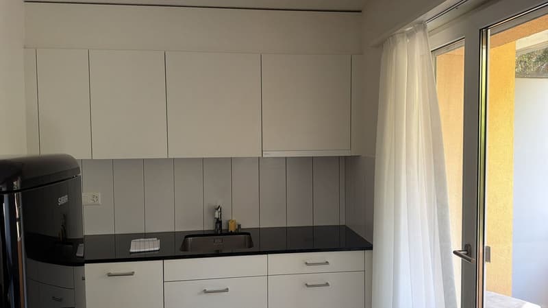 modern kitchen with white cabinets, black countertops, stainless steel sink, dishwasher, washing machine, faucet, window with curtains