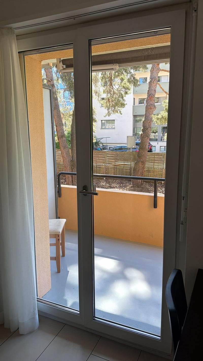 sliding glass door, balcony, chair, view of trees and building