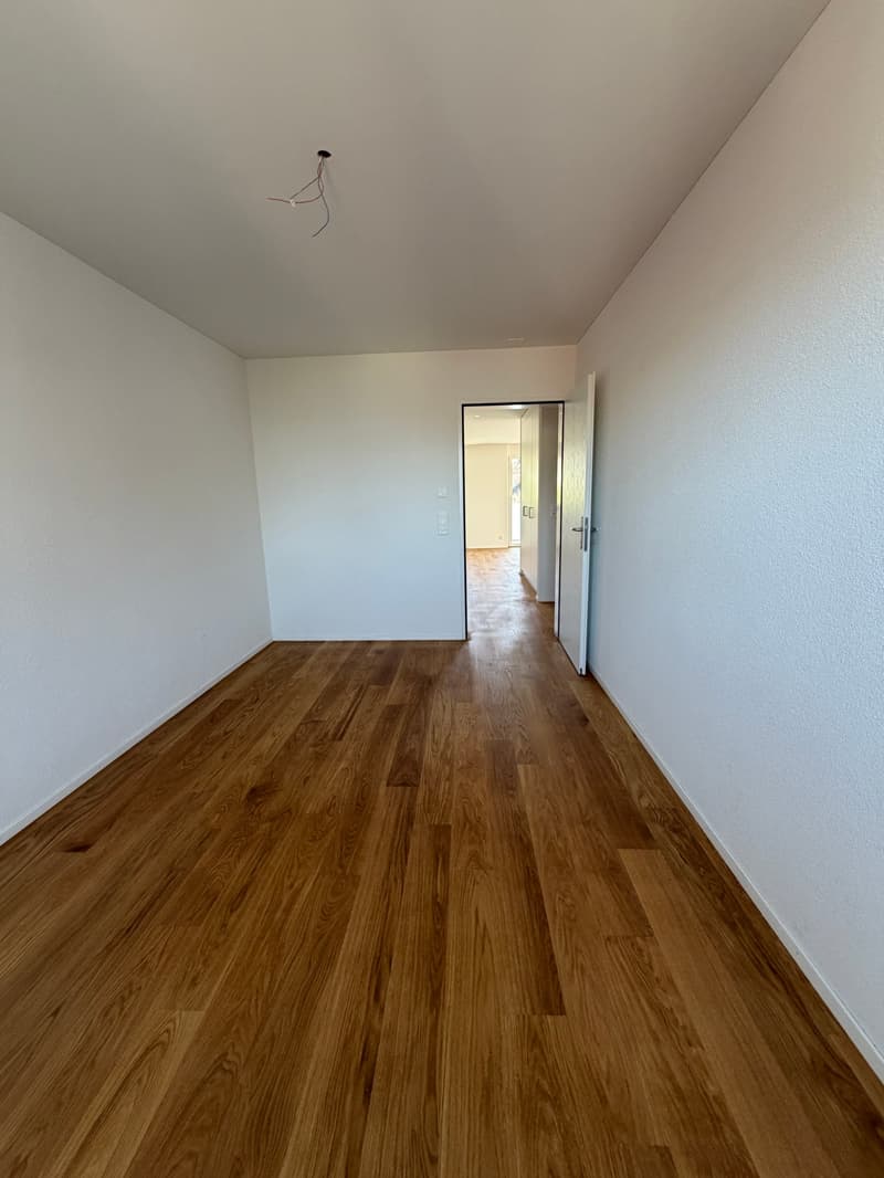 empty room, wooden floor, white walls, open door leading to another room