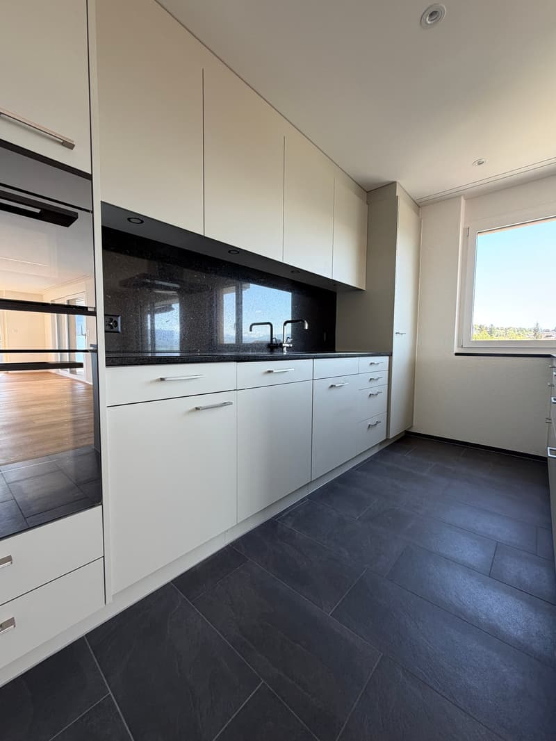 modern kitchen with white cabinets, black countertops, stainless steel sink, dishwasher, and a window