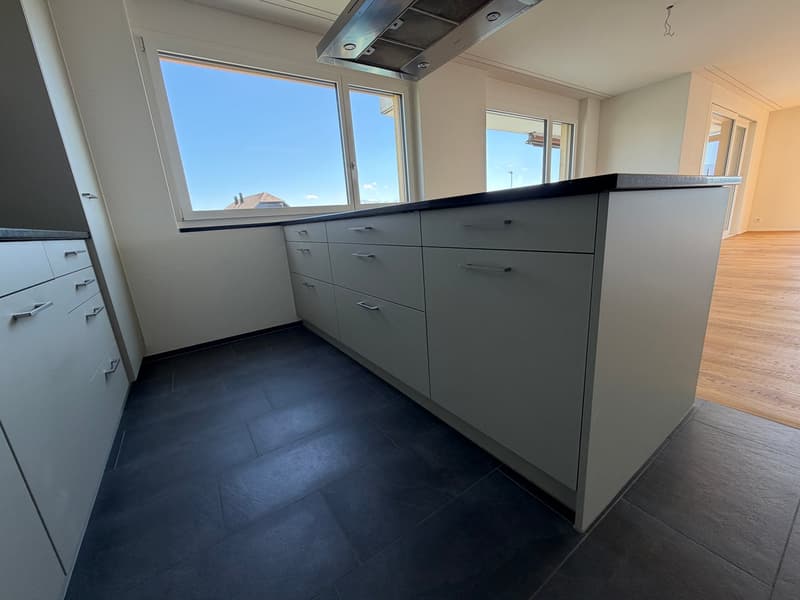 modern kitchen with large windows, gray cabinets, black tiled floor, stainless steel range hood