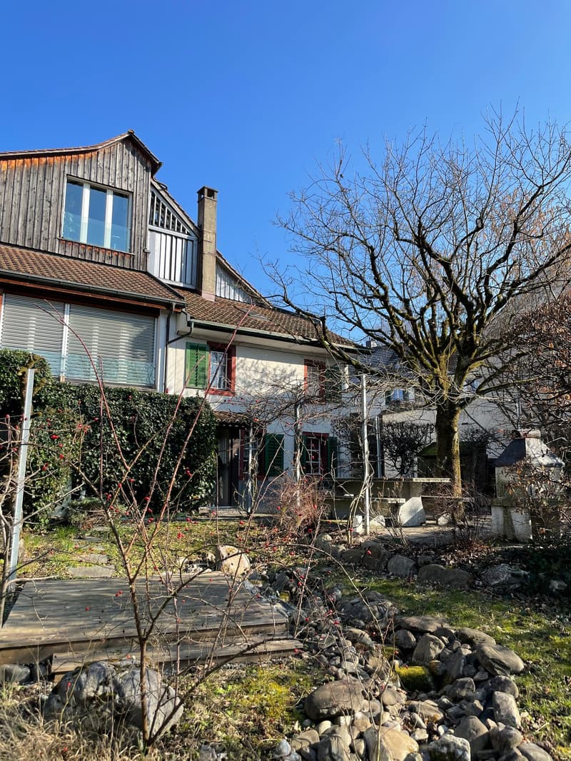 two-story house, wooden balcony, chimney, green shutters, small bushes, grassy yard, trees, pathway