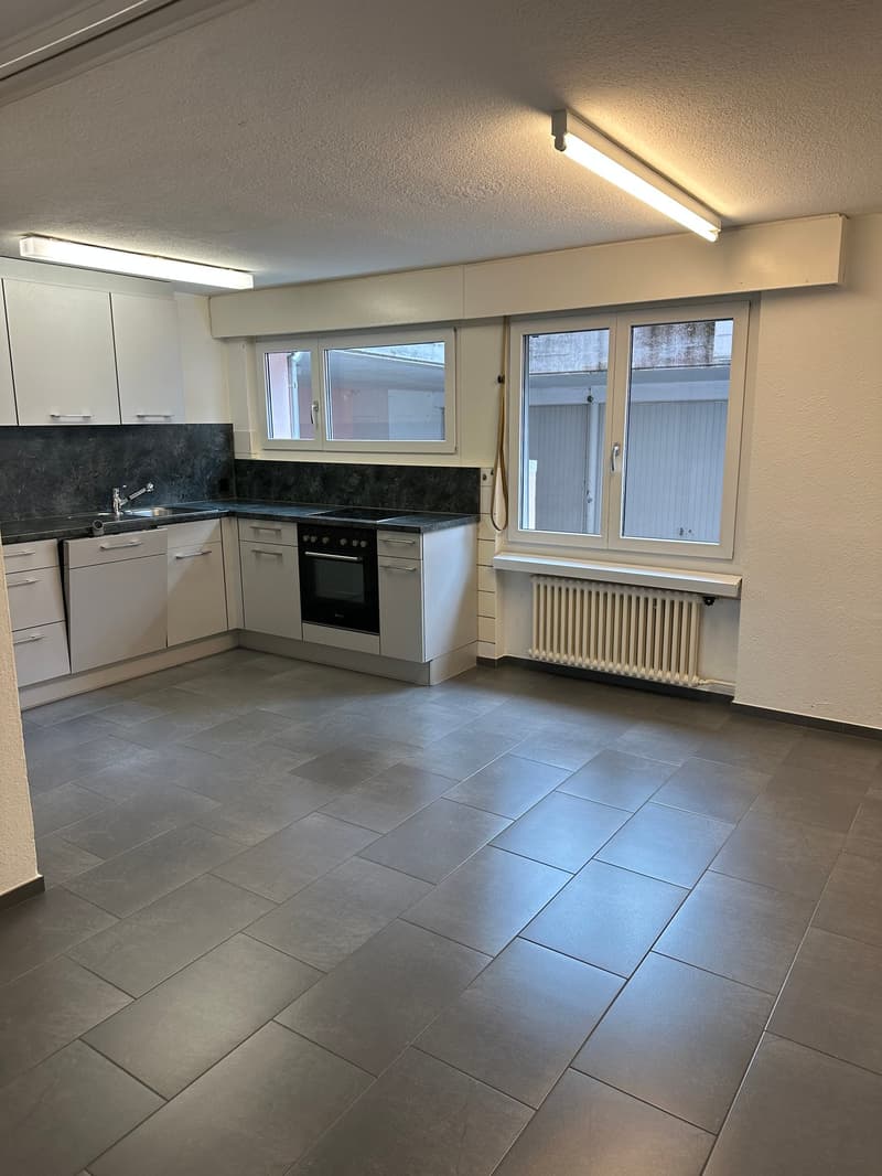 Empty kitchen with appliances, tile flooring, large windows, white cabinets, a stove, a sink, and overhead lights