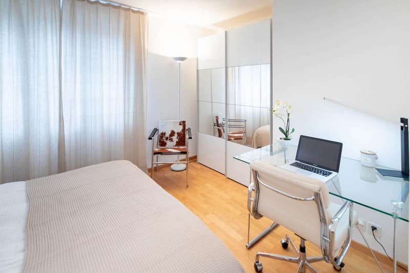 Bedroom with a bed, a desk, a chair, a mirror, and a lamp