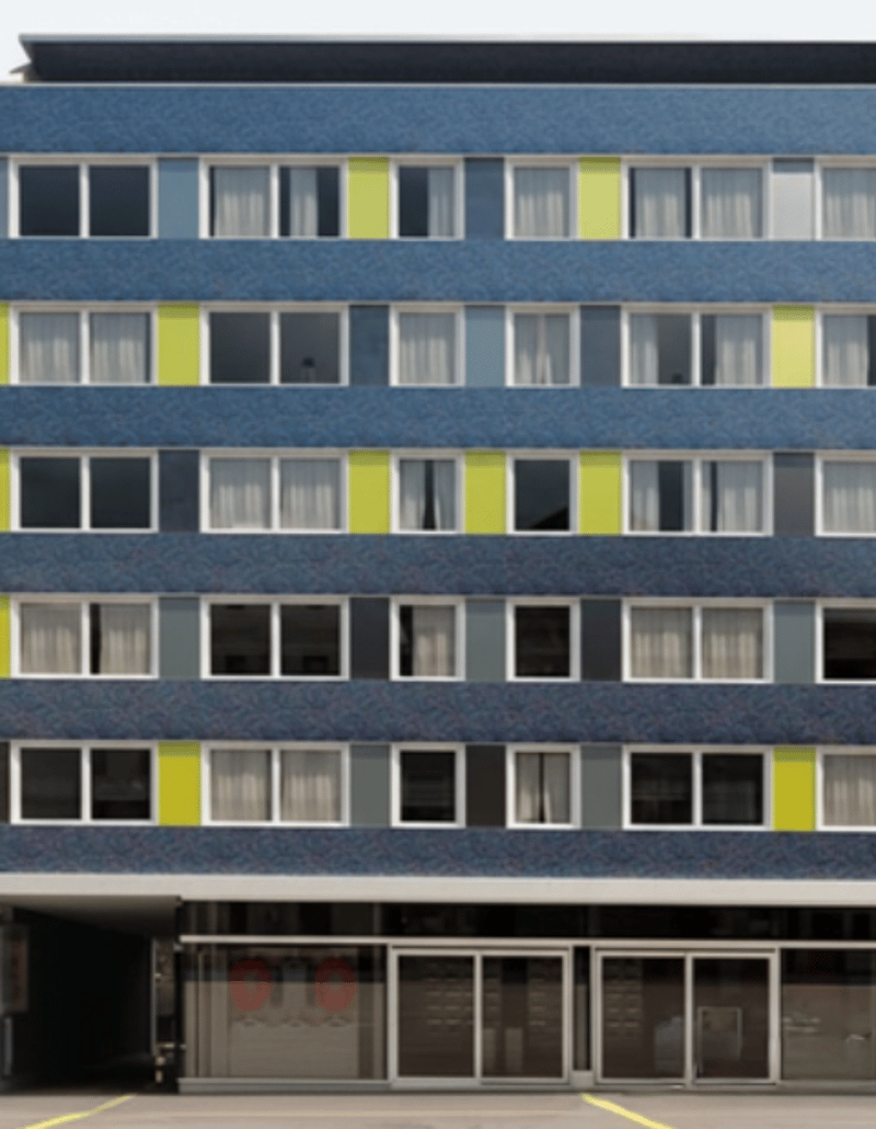 6 story building, glass windows, yellow accents, large entrance with glass doors