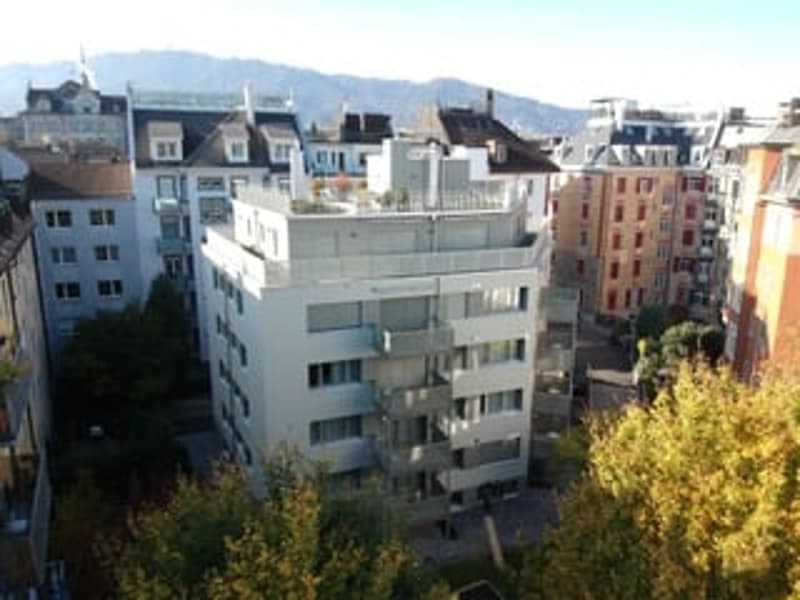 6 story apartment building, brick facade, large terrace on the top floor, mountain view