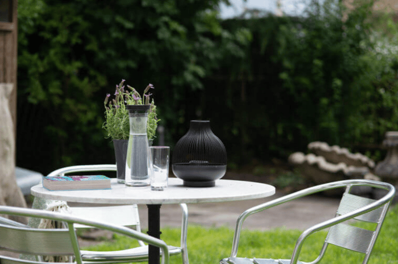 small table with chairs, books, plants, vases, glasses, lamps in the garden
