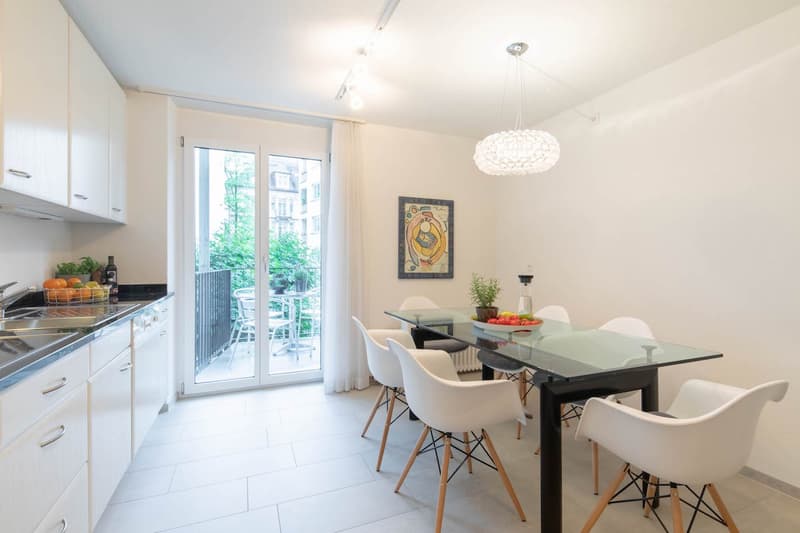 kitchen with dining table, white modern furniture, glass wall leading to balcony