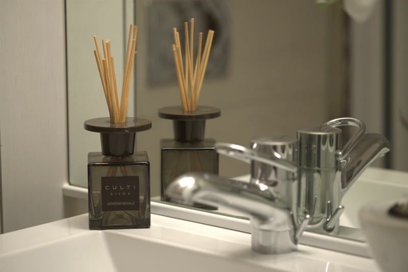 Bathroom with a mirror, a sink, and a bottle of Culti Decor
