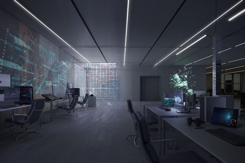 Dark, modern office space with high-tech digital displays on the walls, desks with computers and gaming equipment, and a sleek, minimalist design.