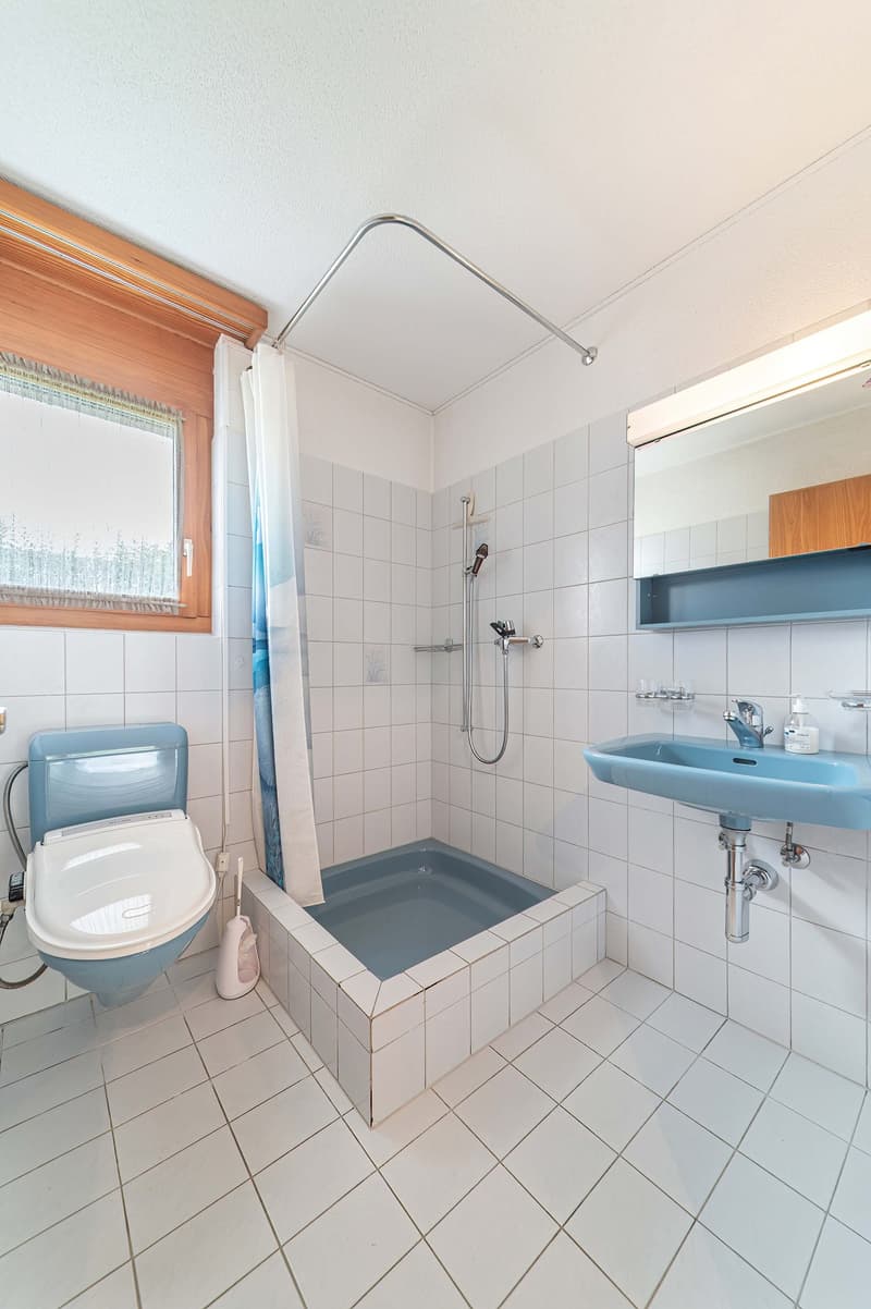 White tiled walls and floor, toilet, shower, sink, mirror