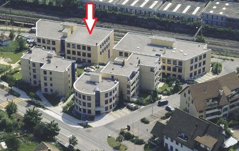 Multi-story office or apartment building with a balcony or terrace visible on the top floor, indicated by the red arrow.