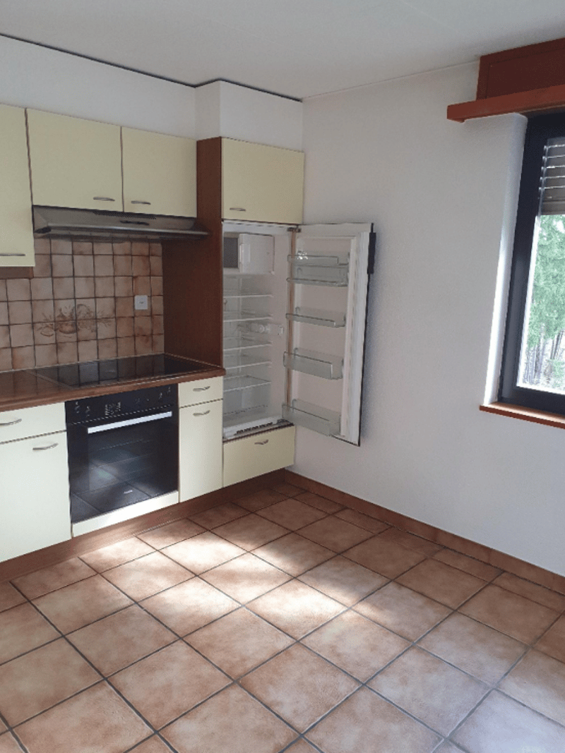 Spacious kitchen with beige cabinets, tiled floor, oven, and refrigerator
