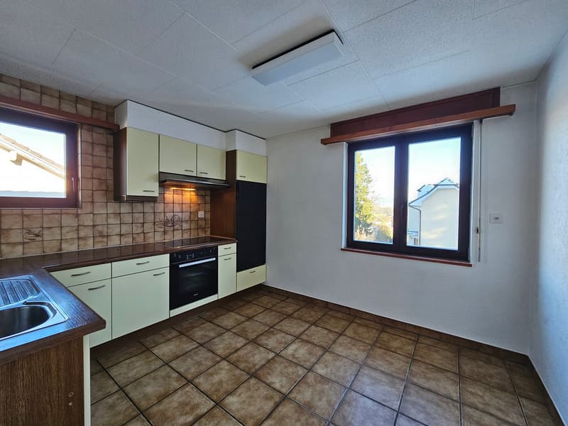 Modern kitchen with tiled floor and white cabinets, built-in oven, and double window