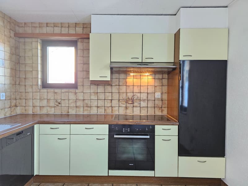 modern kitchen with white tiles, black stove, black refrigerator, green cupboards, dishwasher, wooden countertop