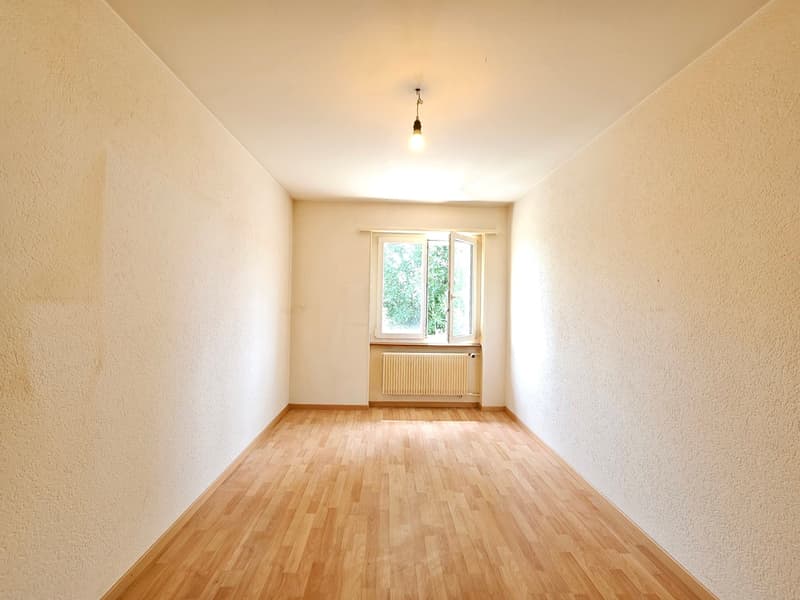 empty room with wooden floor, white walls, ceiling lamp, window, radiator