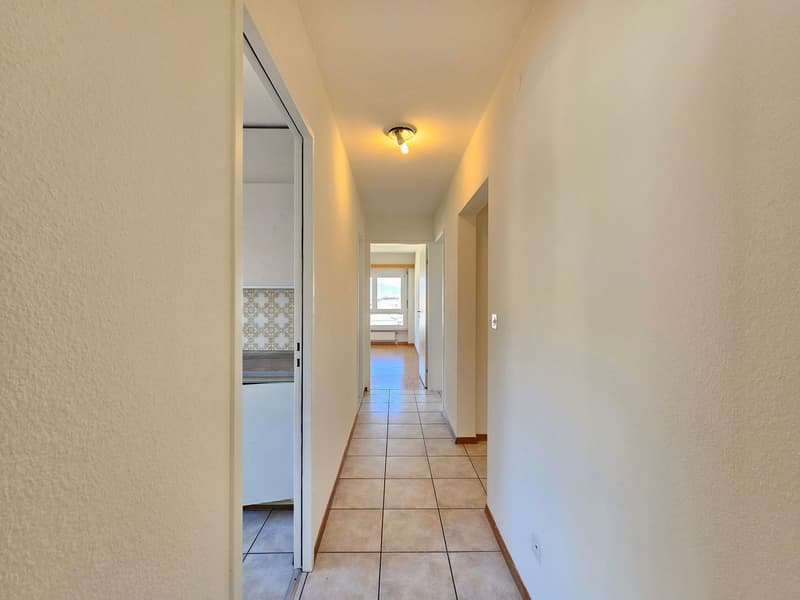 empty hallway with tiled floor and white walls, hallway light on the ceiling