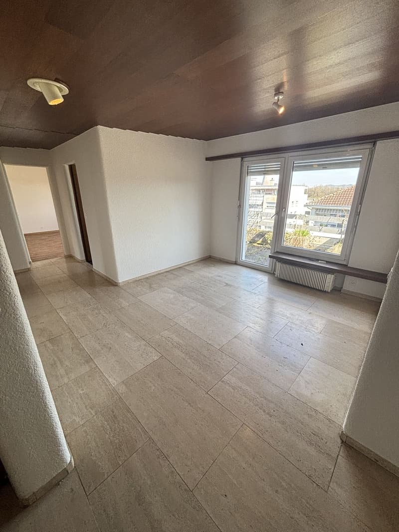 Spacious room with white walls, tile flooring, and large windows providing natural light. The room appears to be empty, ready for furnishing and decorating.