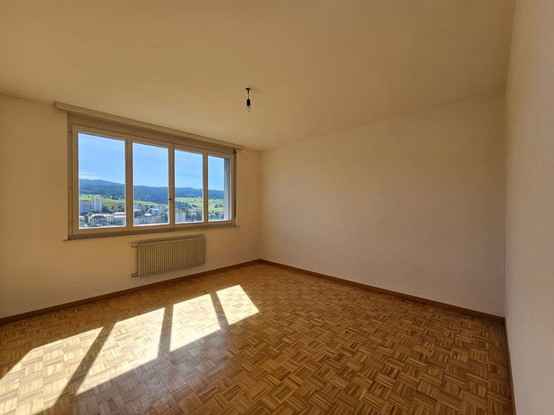Empty room, large window, wooden parquet floor, radiator