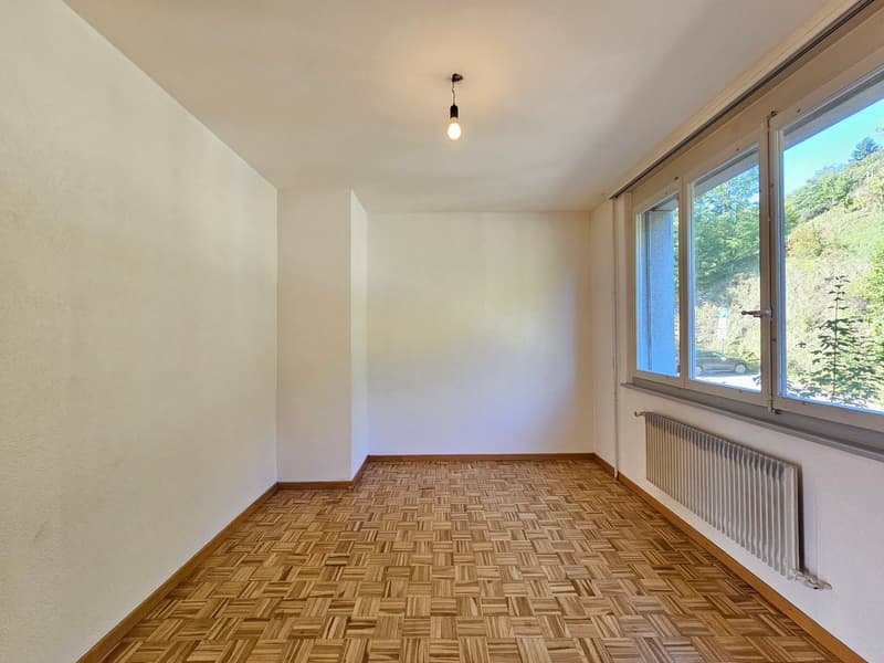 an empty room with wooden flooring, white walls, a window, and a ceiling light