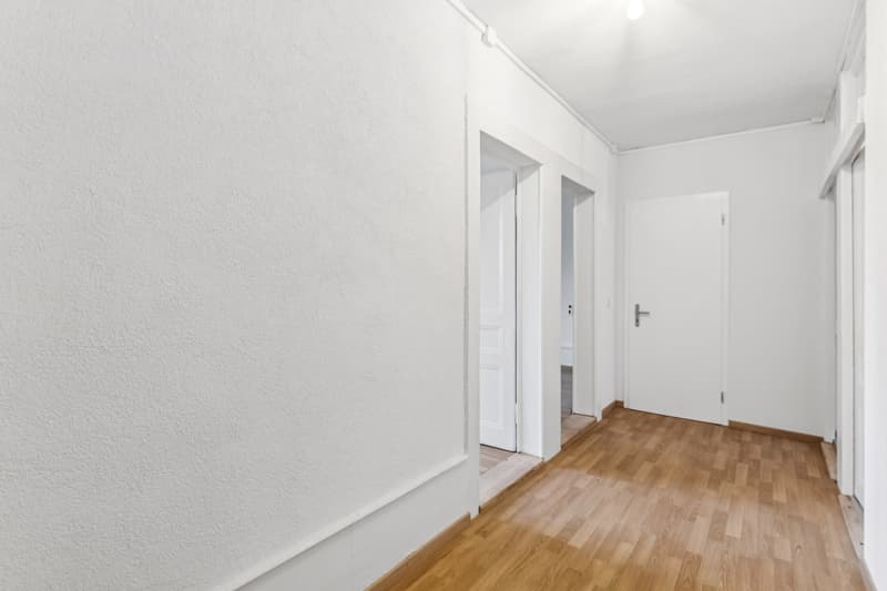 modern minimalist room with white walls, wooden floor, doors