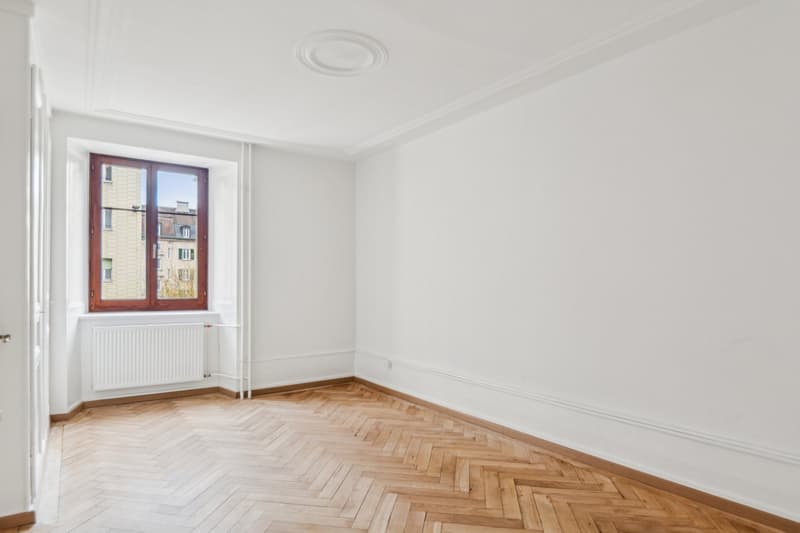 empty room with parquet floor, white walls, radiator, and a window
