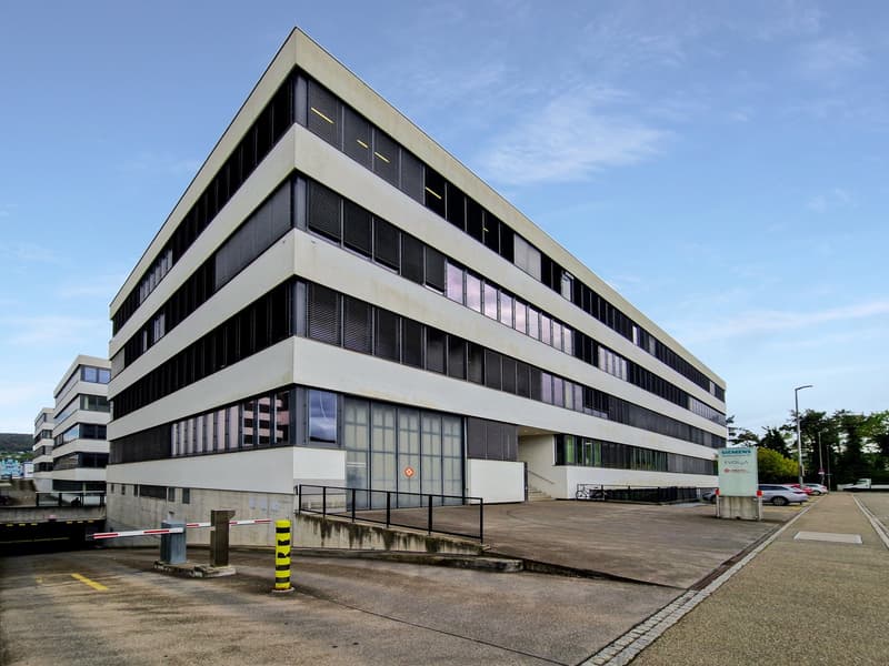 modern office building, multiple windows, concrete exterior, multiple floors, parking area in front