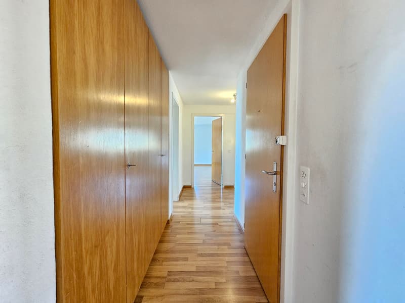 wooden cabinets, wooden floor, white walls, open door, light on the ceiling