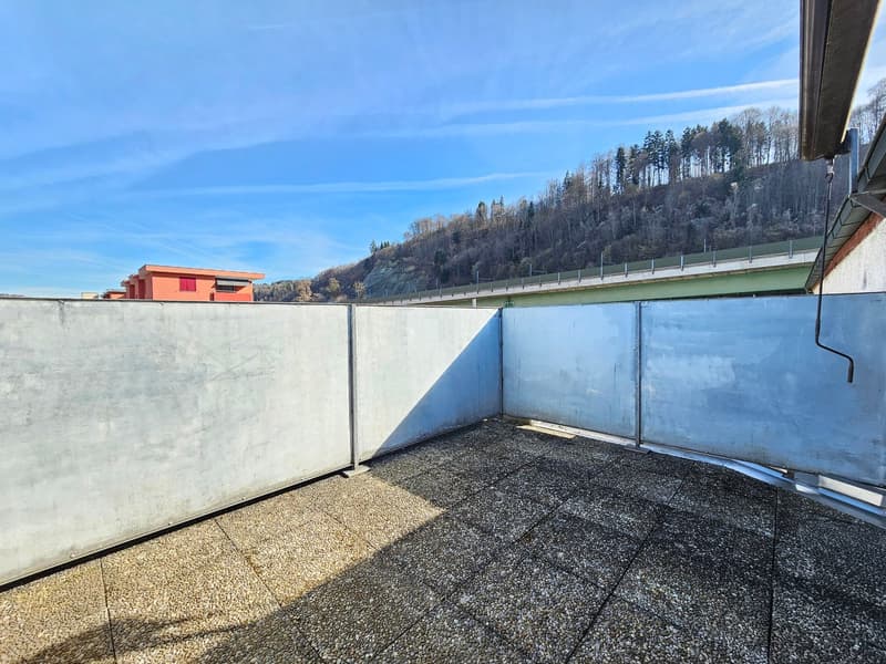 Concrete floor, concrete walls, gravel surface, clear sky, distant building, mountain