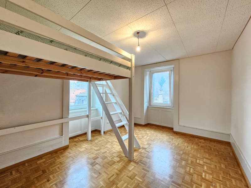 Bunk bed with ladder, wooden floor, two windows, white walls, hanging light
