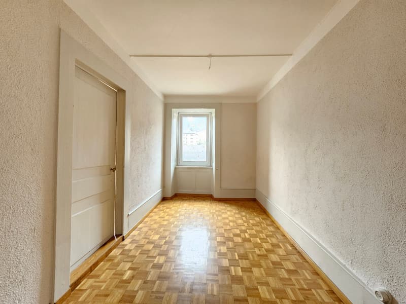 wooden parquet floor, tall white walls, small window, door