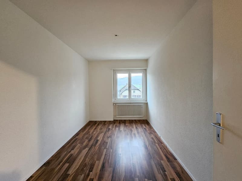 empty room, wooden floor, white walls, window with white radiator, door