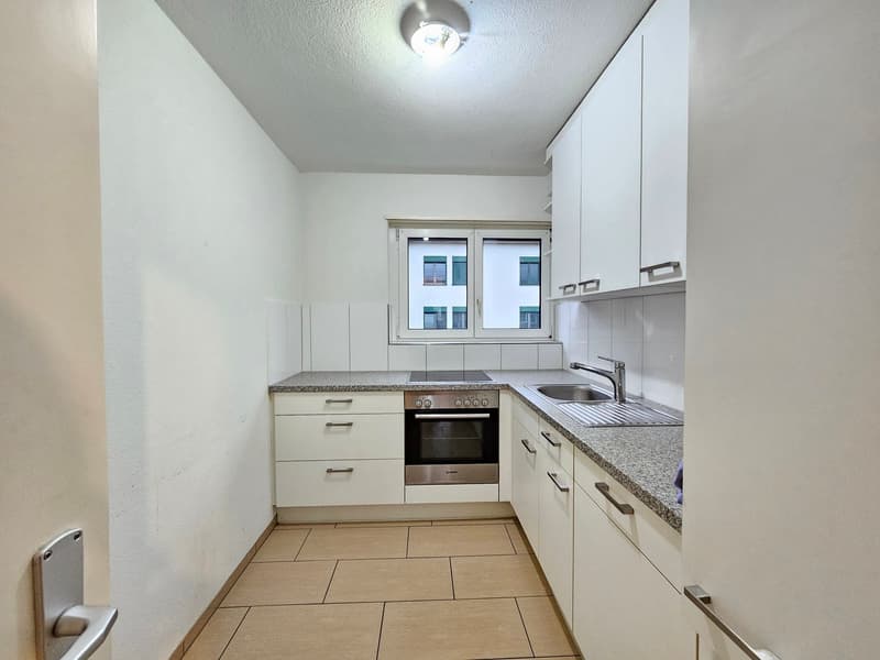 modern kitchen with built-in appliances, granite countertops, white cabinetry, windows, wooden floor