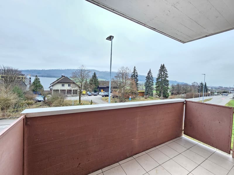 balcony with white tiled flooring, brown railings, street view, view of houses and mountain