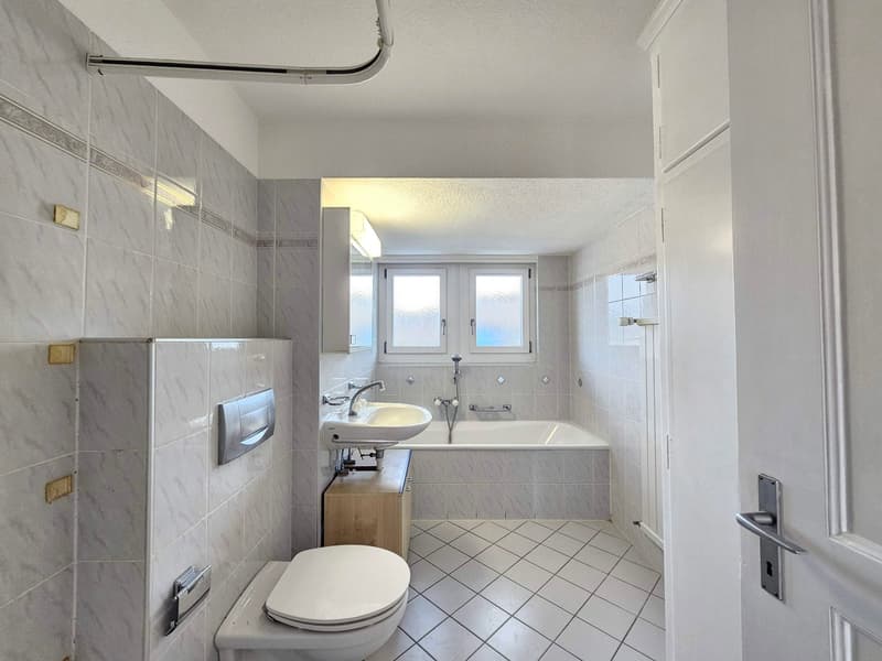 Modern bathroom, white tiles, bathtub, sink, toilet, small window