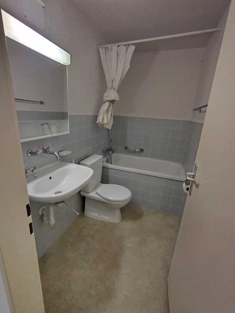 Bathroom with bathtub, toilet, sink, mirror, and blue tiles.