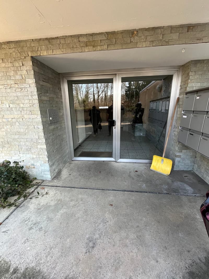 Concrete building with brick wall, glass doors, and a snow shovel on the side
