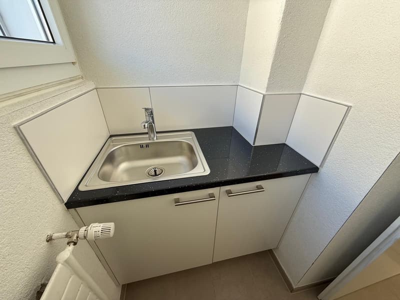 compact sink, white cabinets, tiled walls, floor heater